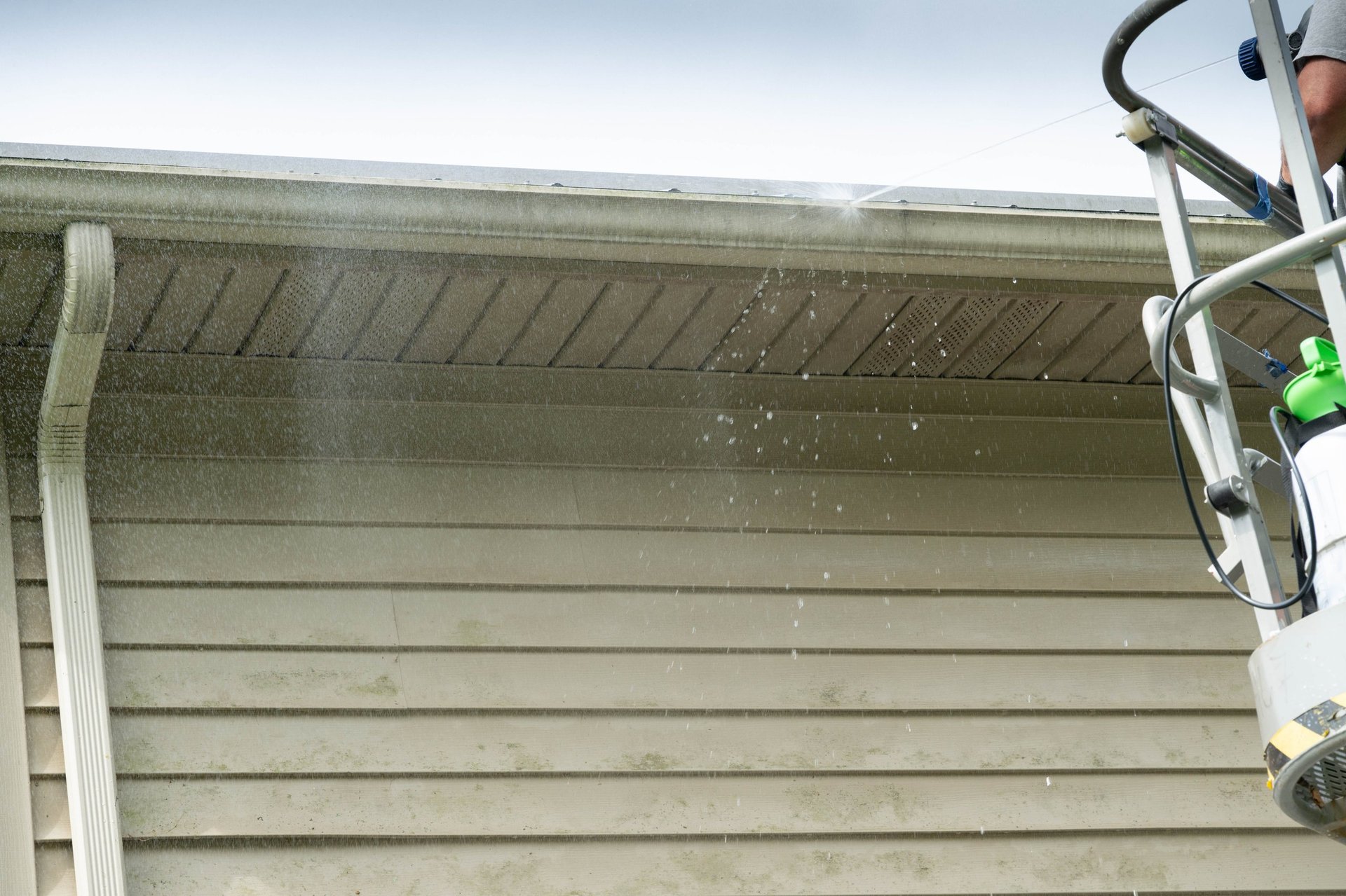 House washing soft wash cleaning the siding of a Spokane home from a lift