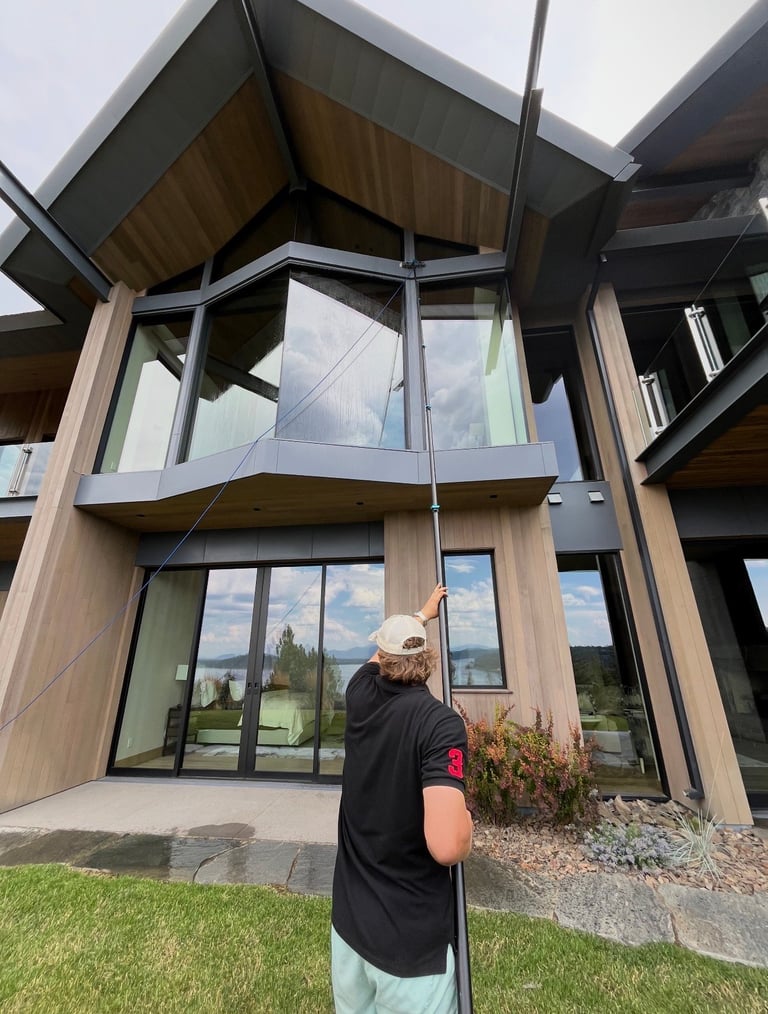 Person in black shirt holding a rope in front of modern A-frame house with large windows and wooden siding